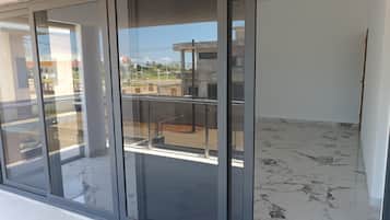 Ein modernes Gebäude mit einer Glastür, die auf einen Balkon mit Metallgeländer führt.