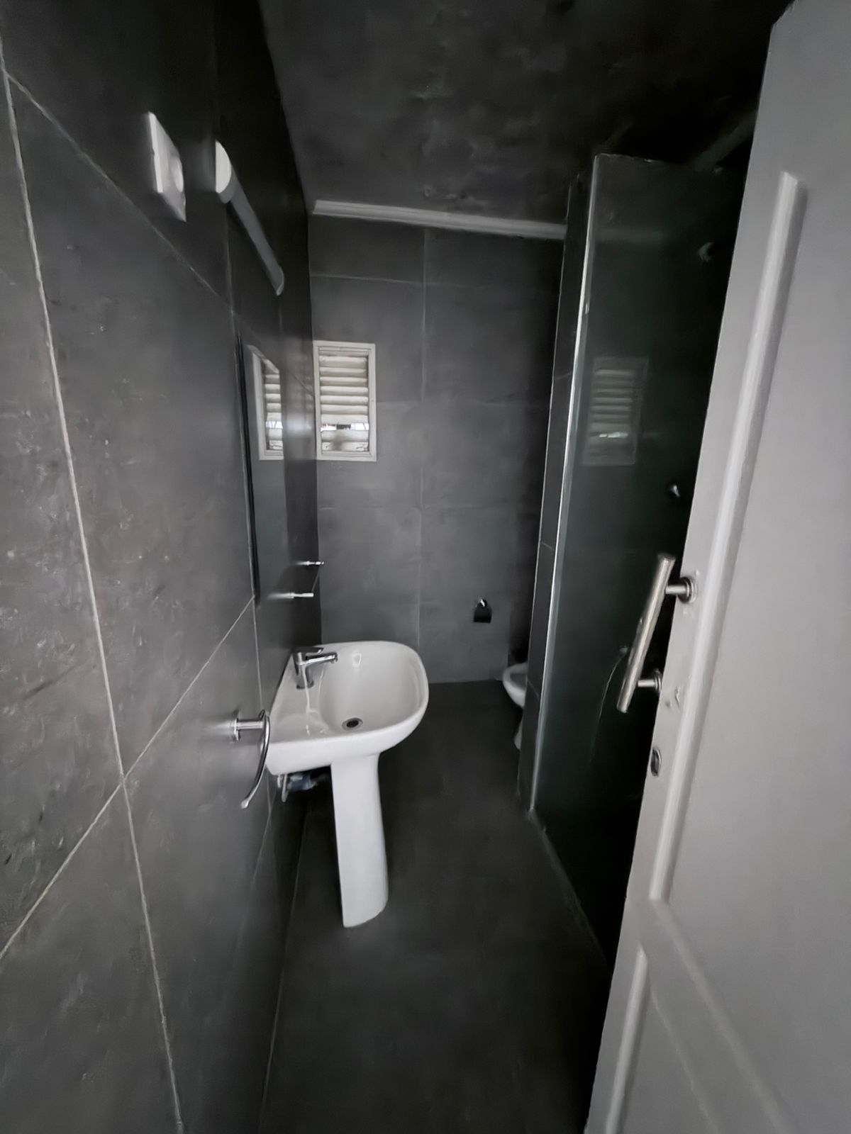 Et badeværelse med et håndvaskarrangement, toilet og bruseniche.