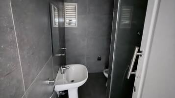 Et badeværelse med et håndvaskarrangement, toilet og bruseniche.