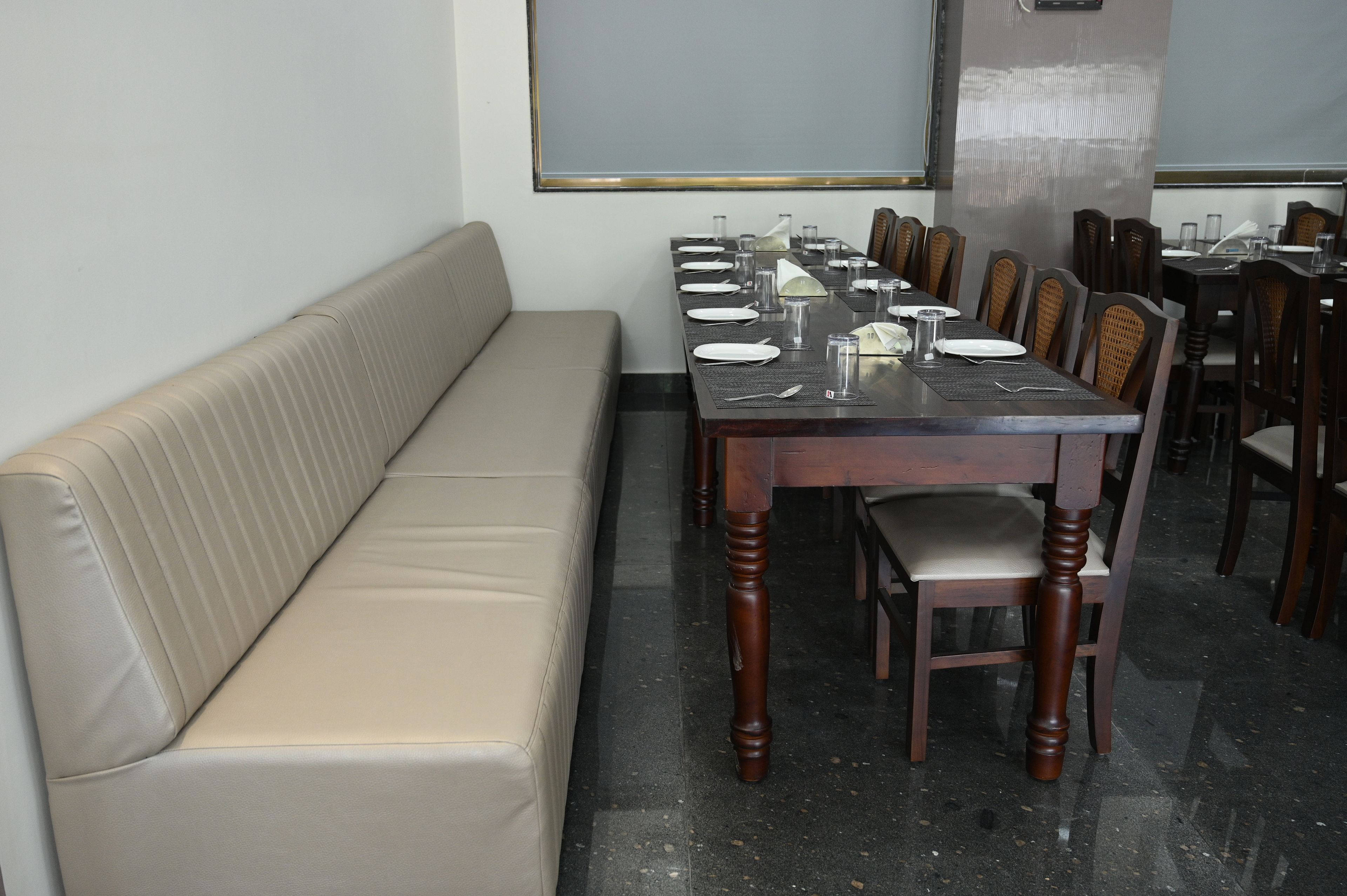 Un espace repas avec une longue table dressée pour un repas, entourée de chaises.