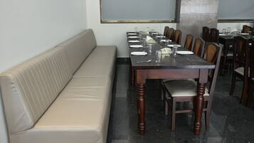 Un espace repas avec une longue table dressée pour un repas, entourée de chaises.