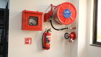 Un extincteur fixé au mur, une alarme incendie et un détecteur de fumée.