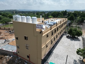 A multi-story hotel with a flat roof, several water tanks, and a sign indicating it is the 'Hotel Rahi Inn.'