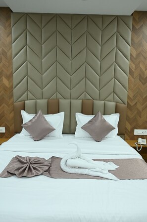 Una habitación de hotel con una cama grande, un cabecero con diseño geométrico, dos almohadas, una manta y una toalla.