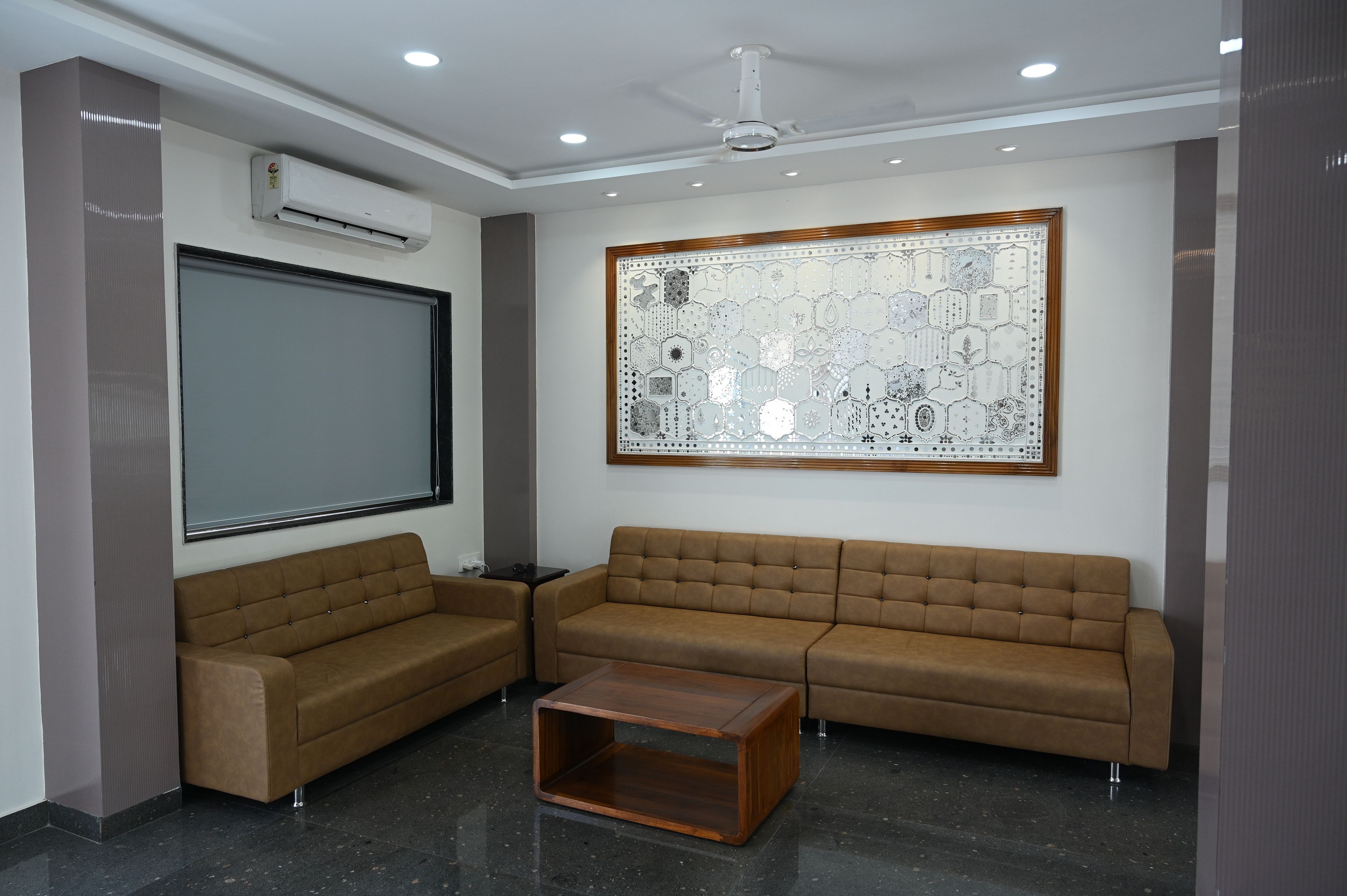 Uma sala de estar moderna com um sofá seccional, uma mesa de centro, um espelho grande e um painel de vidro decorativo.