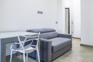 Una sala de estar moderna con un sofá gris, una silla blanca y una mesa con cubierta de vidrio.