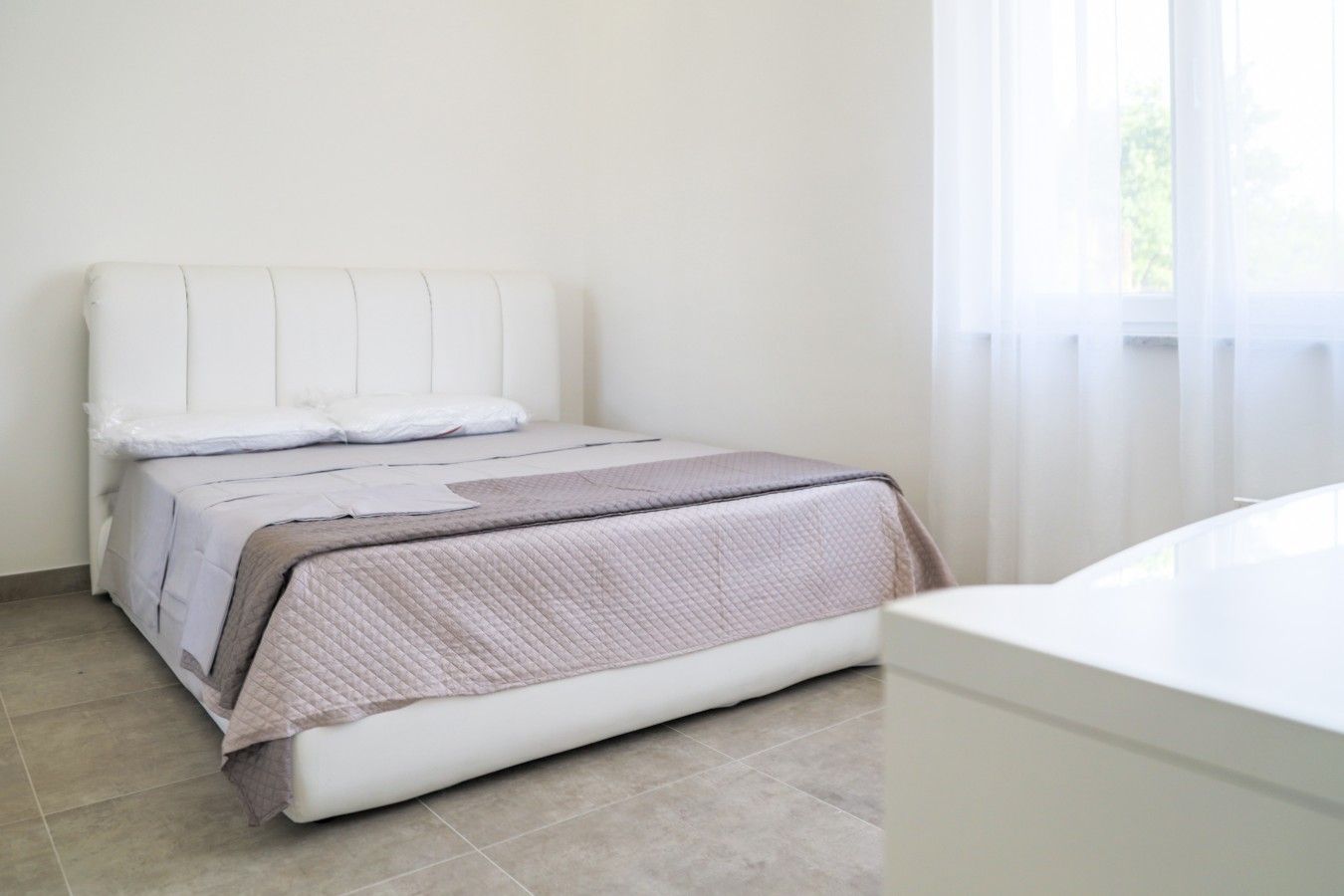 Une chambre à coucher avec un lit, une table de chevet et une fenêtre avec des rideaux.