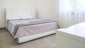 Un dormitorio con una cama, una mesita de noche y una ventana con cortinas.