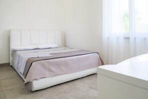 Un dormitorio con una cama, una mesita de noche y una ventana con cortinas.