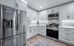 A modern kitchen with stainless steel appliances, white cabinetry, and a patterned rug. - Margaret Manor - South Lake Tahoe Retreat (South Lake Tahoe)