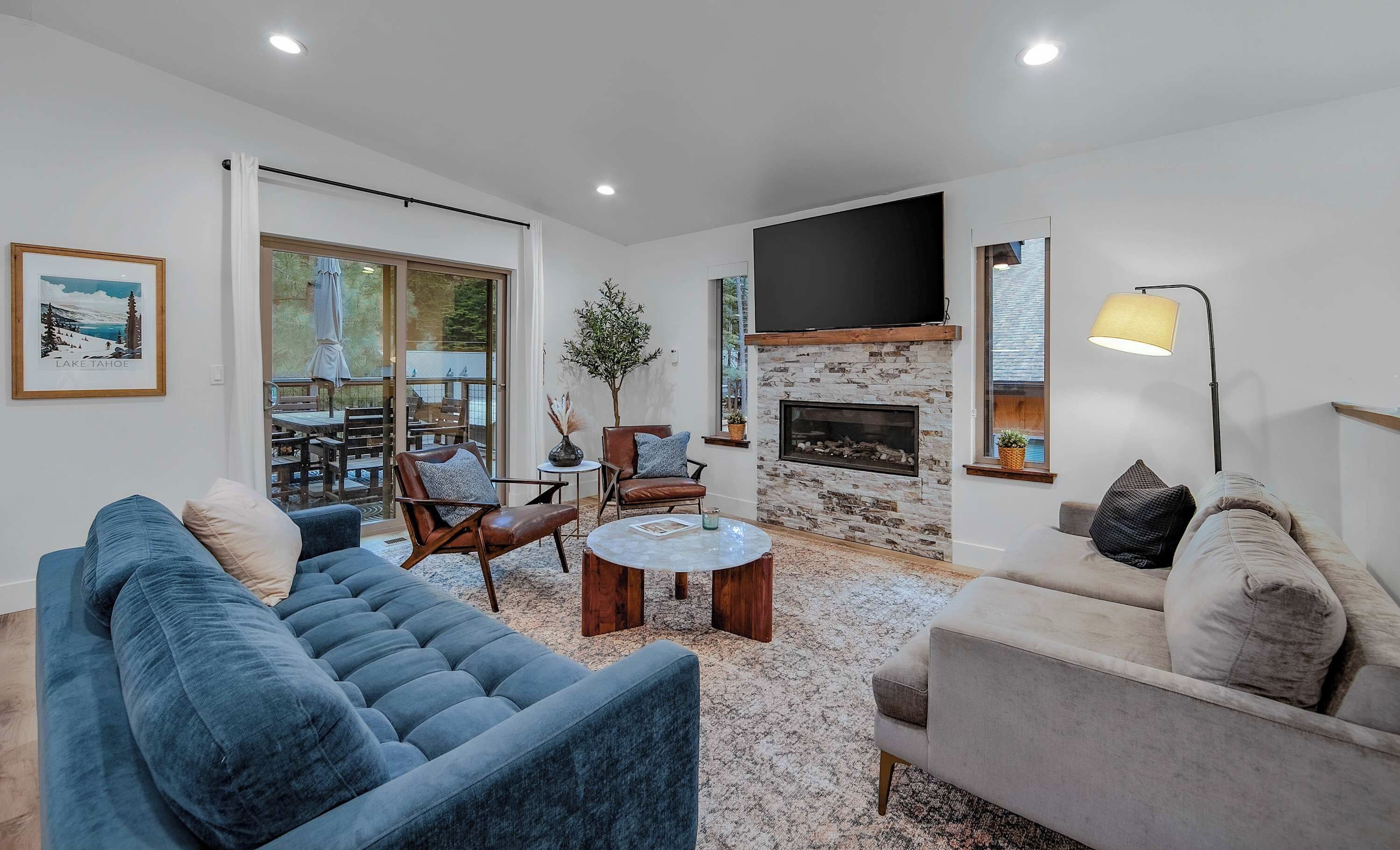 A modern living room with a fireplace, comfortable seating, and a large window.