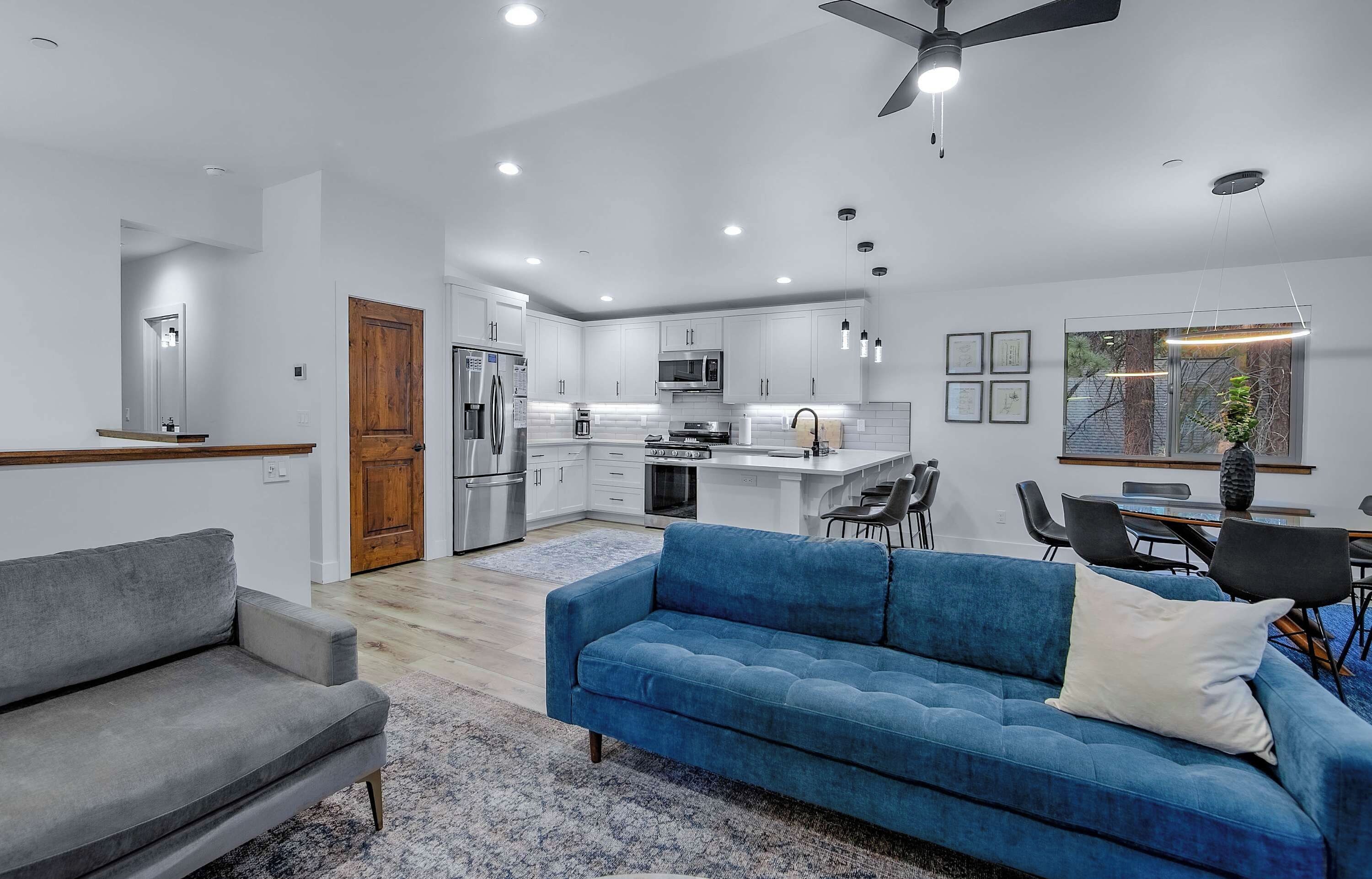 Een moderne keuken met witte kasten, roestvrijstalen apparatuur en een zithoek met een blauwe bank en een kleine tafel.