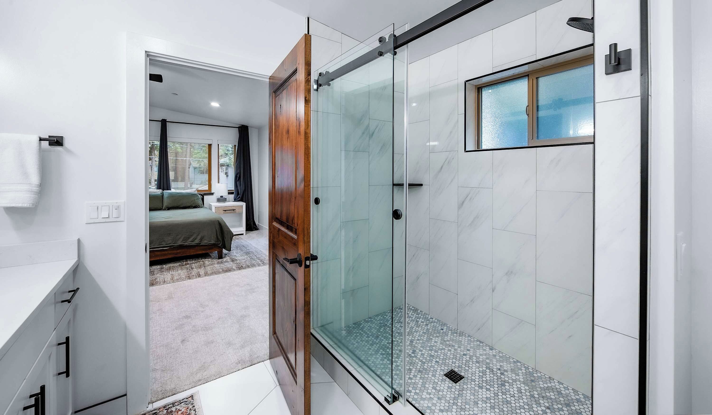 A modern bathroom with a glass shower enclosure, a visible toilet, and a sink.