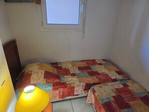 A small room with a bed, a window, and a lamp. - Air-conditioned apartment with pool near the coves (Fréjus)
