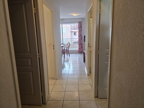 A hallway with a tiled floor leading to a balcony with chairs and a table. - Air-conditioned apartment with pool near the coves (Fréjus)