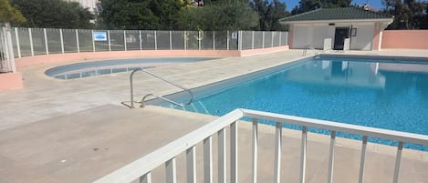 A swimming pool with a white fence, a small building, and a clear sky.