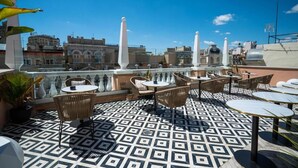 Terraço no telhado com piso estampado, mobiliário externo e vista panorâmica da cidade.
