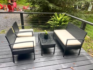 Eine Terrasse mit Gartenmöbeln, darunter zwei Stühle, ein Sofa und ein kleiner Tisch mit einem Blumentopf.