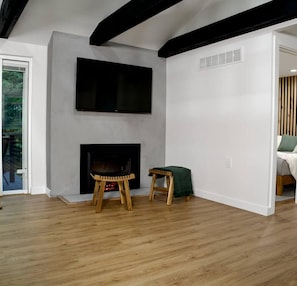 Ein modernes Wohnzimmer mit Kamin, einem an der Wand montierten Flachbildfernseher und Holzboden.