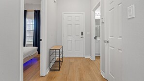 A hallway with a bed, a door, a shelf, and a window with curtains. - 4BR Bella Vida Resort Pool & BBQ Near Disney (Kissimmee)