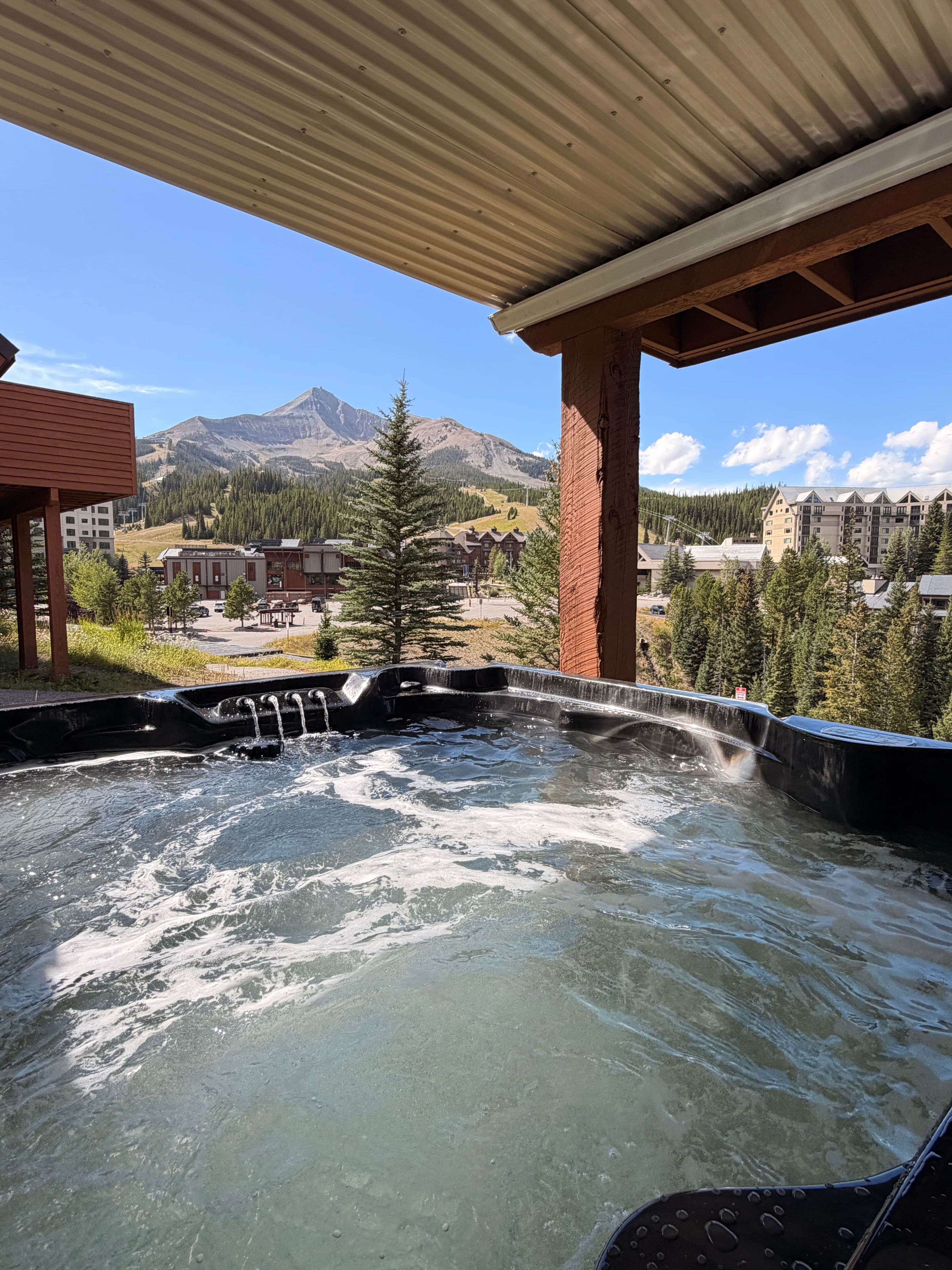 Ein Whirlpoolbereich mit Blick auf Berge und einen Gebäudekomplex im Hintergrund.