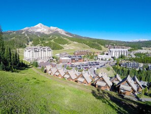 A mountain resort with multiple lodging options including large hotels and smaller cabins, surrounded by lush greenery and a prominent mountain peak. - NEW LISTING! Cozy Big Sky Luxury Escape- Ski In/Ski Out -Private outdoor hot tub (Big Sky)