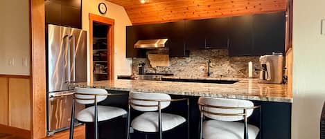 Una cocina moderna con encimera de granito, electrodomésticos de acero inoxidable y horno empotrado.