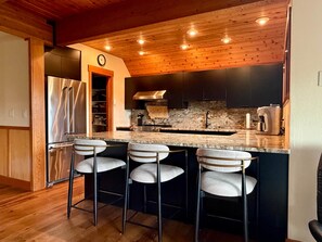 Una cocina moderna con encimera de granito, electrodomésticos de acero inoxidable y horno empotrado.
