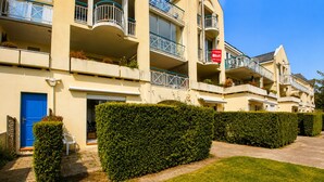 A multi-story hotel with balconies, a blue door, and a sign indicating availability for rent. - Studio with terrace, swimming pool and parking (Guérande)