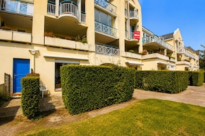 A multi-story hotel with balconies, a blue door, and a sign indicating availability for rent. - Studio with terrace, swimming pool and parking (Guérande)