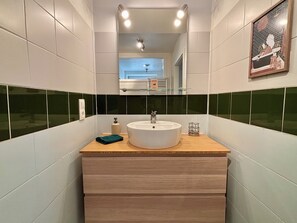 Ein Badezimmer mit einem runden Waschbecken, einem Spiegel darüber und einem Handtuch auf der Ablagefläche.