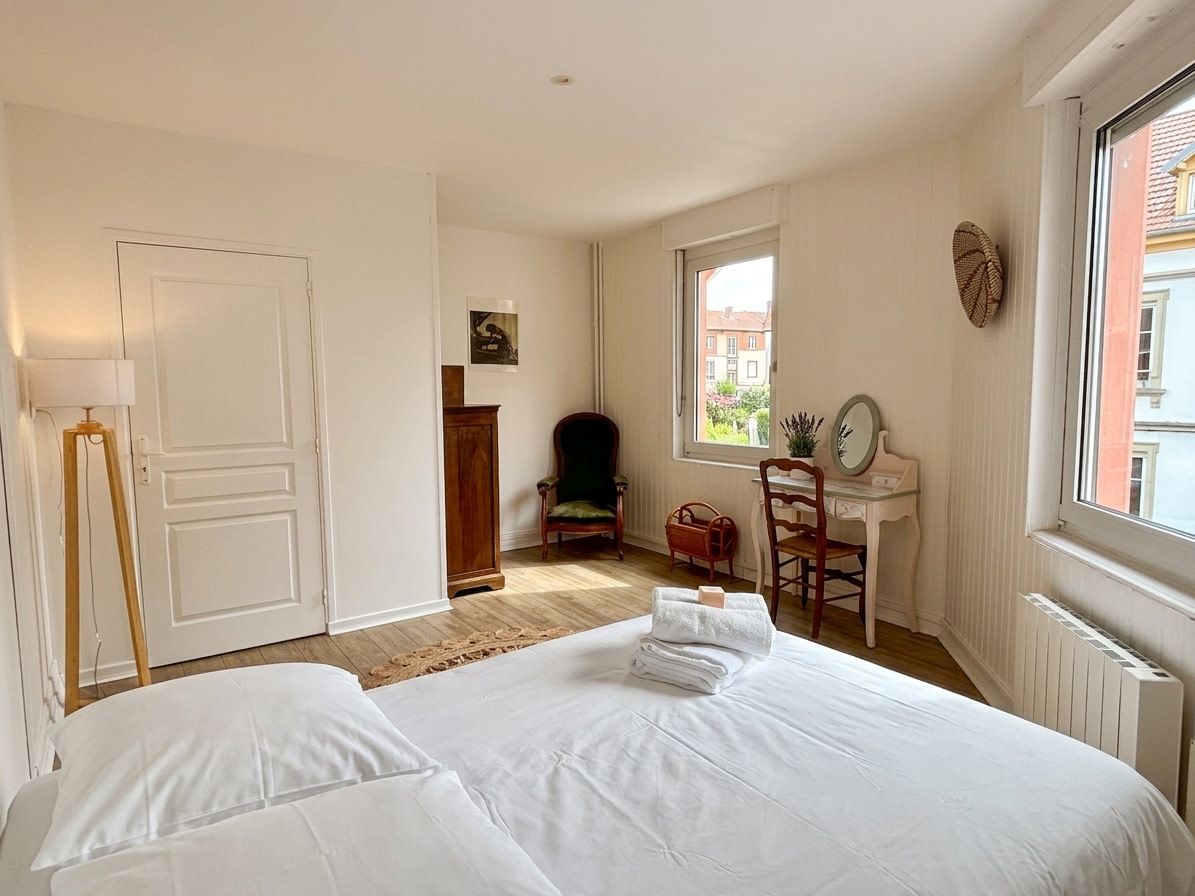 A bedroom with a bed, a desk, a chair, and a window.