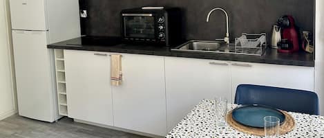 A compact kitchen with white cabinets, a microwave, a toaster oven, and a sink.