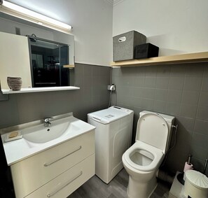 Une salle de bain moderne avec un lavabo blanc, des toilettes et un lave-linge.