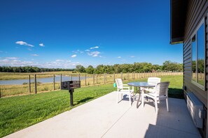 Un patio con mobiliario exterior, una parrilla y vista al lago.