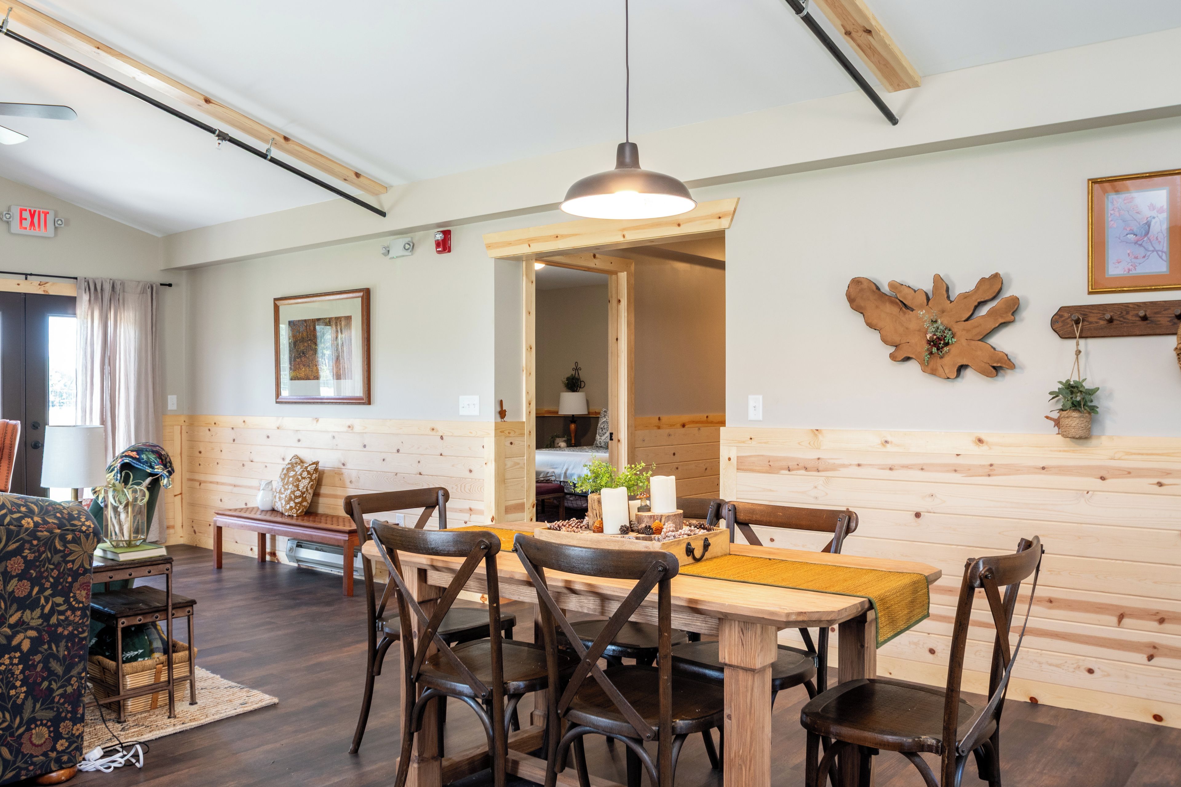 A dining area with wooden furniture, a hanging light fixture, and a wooden wall panel.