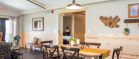 A dining area with wooden furniture, a hanging light fixture, and a wooden wall panel.
