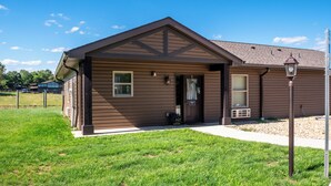 A single-story house with a brown exterior, a front porch, and a small front yard. - Located in Peoria, Illinois Legacy Cabin 8 offers a luxury retreat immersed in nature, with stunning views of roaming bison and elk just outside your window. This 2-bedroom, 1-bath cabin features a comfortable living area with plush seating and a coz (Hanna City)
