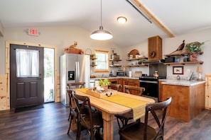 Una cocina moderna con armarios de madera, una isla central y un comedor con sillas de madera.