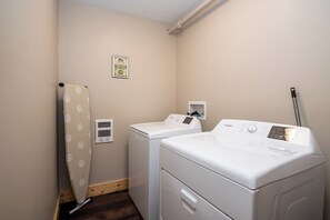 A laundry room with a washer and dryer, a wall-mounted heater, and a small electrical outlet. - Located in Peoria, Illinois Legacy Cabin 8 offers a luxury retreat immersed in nature, with stunning views of roaming bison and elk just outside your window. This 2-bedroom, 1-bath cabin features a comfortable living area with plush seating and a coz (Hanna City)