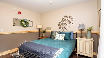 Un dormitorio con cama, mesitas de noche, cómoda, espejo y decoración en la pared.