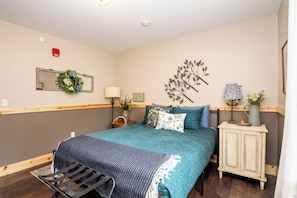A bedroom with a bed, bedside tables, a dresser, a mirror, and a wall decoration. - Located in Peoria, Illinois Legacy Cabin 8 offers a luxury retreat immersed in nature, with stunning views of roaming bison and elk just outside your window. This 2-bedroom, 1-bath cabin features a comfortable living area with plush seating and a coz (Hanna City)