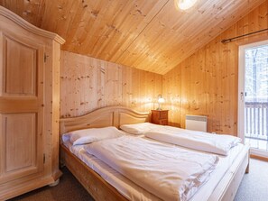 A wooden-paneled room with a double bed, a nightstand, and a window with a view of trees. - Cabin in Annaberg With Swimming Pool (Annaberg-Lungoetz)