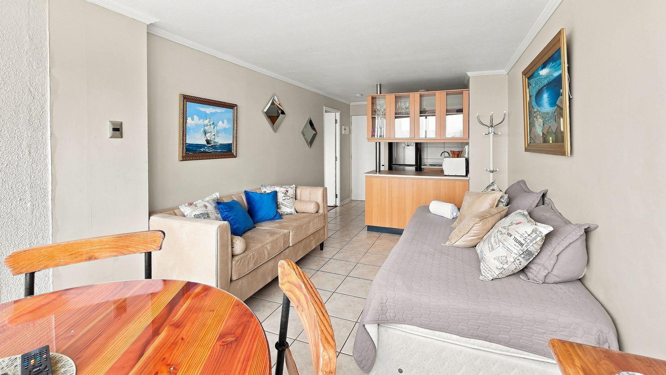 A compact living space with a kitchenette, a dining area, and a seating area with a sofa and a bed.