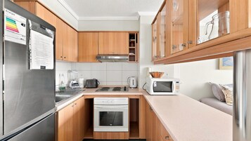 Una cocina moderna con armarios de madera, un refrigerador de acero inoxidable, un horno empotrado y un microondas.