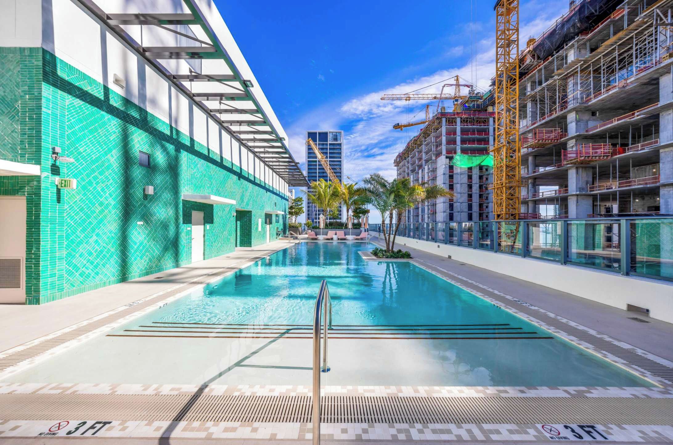 Une piscine offrant une vue dégagée sur les bâtiments environnants et le chantier de construction.