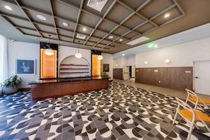 A reception area with a reception desk, a patterned floor, and a ceiling with recessed lighting. - The Crosby Hotel World Center (Miami)