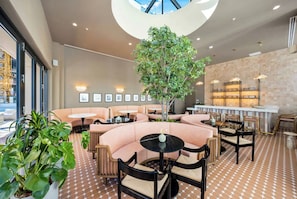 Ein stilvoller Lounge-Bereich mit Sitzmöglichkeiten, einem zentralen Baum und einer Bar.