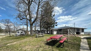 Un camping con mesas de picnic, cabañas y un edificio grande con un muelle.