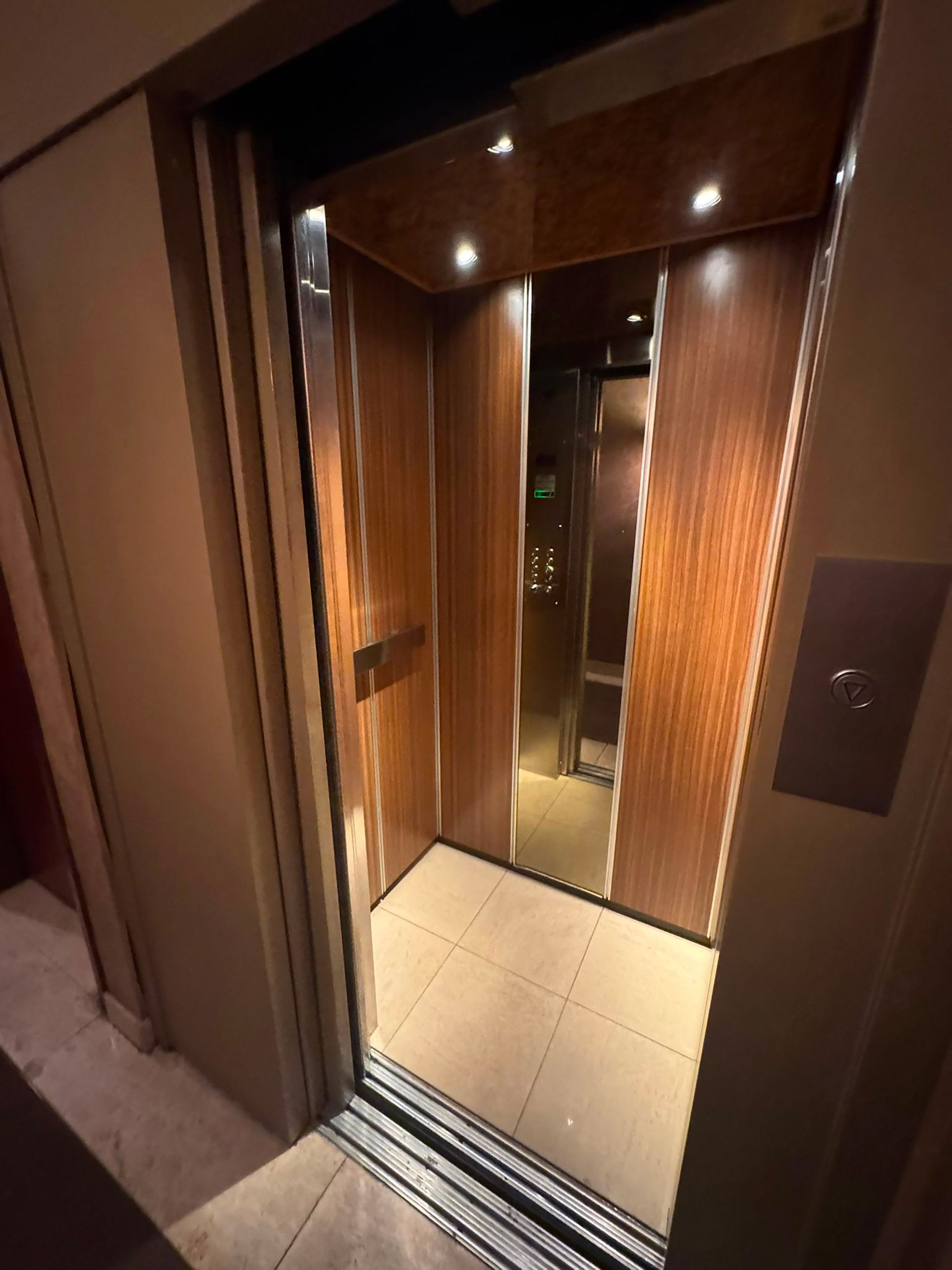 An elevator with a metallic interior and wooden paneling on the walls.